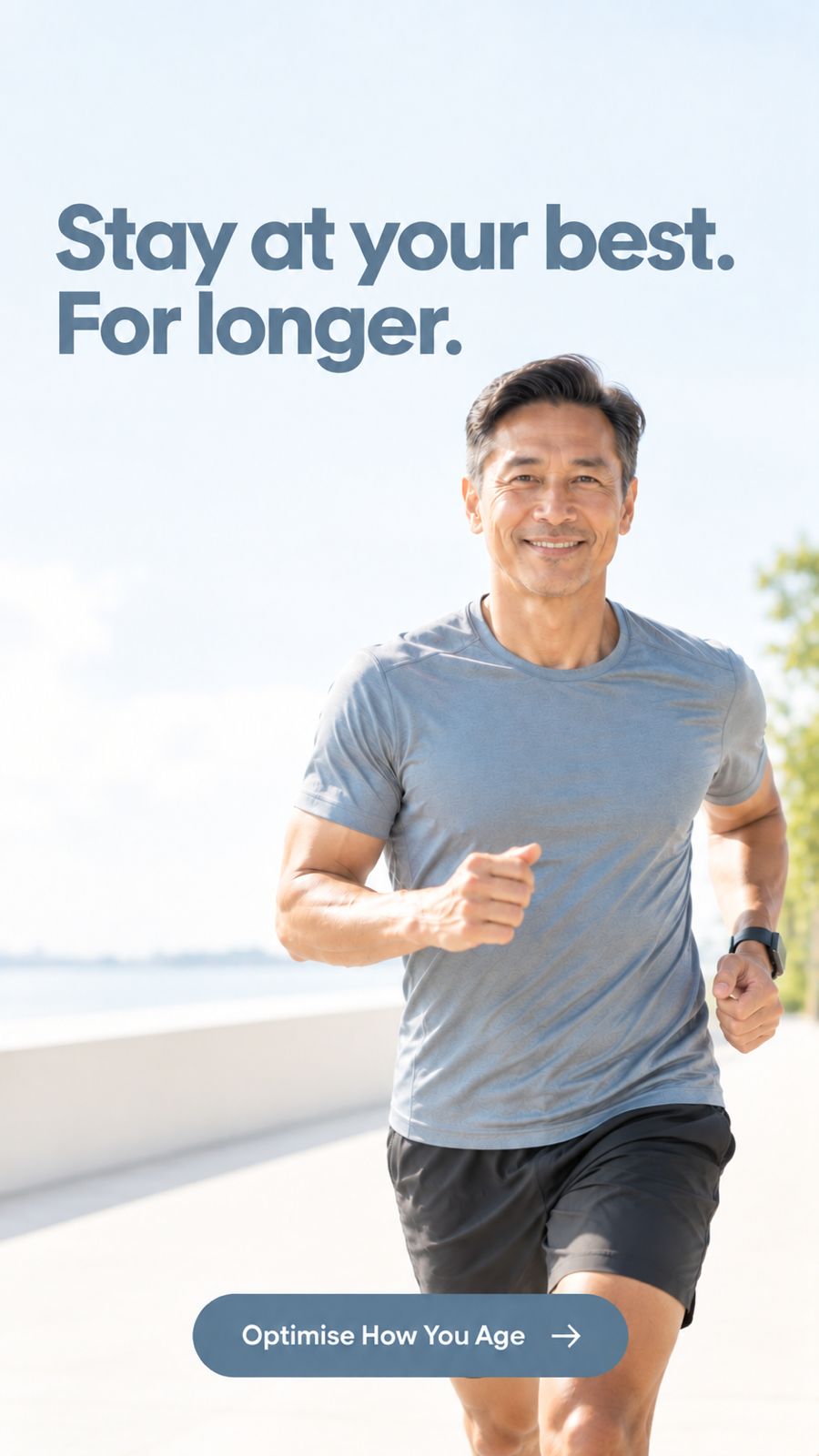 A smiling man in a gray athletic t-shirt and black shorts jogging outdoors on a sunny day, with the text 'Stay at your best. For longer.